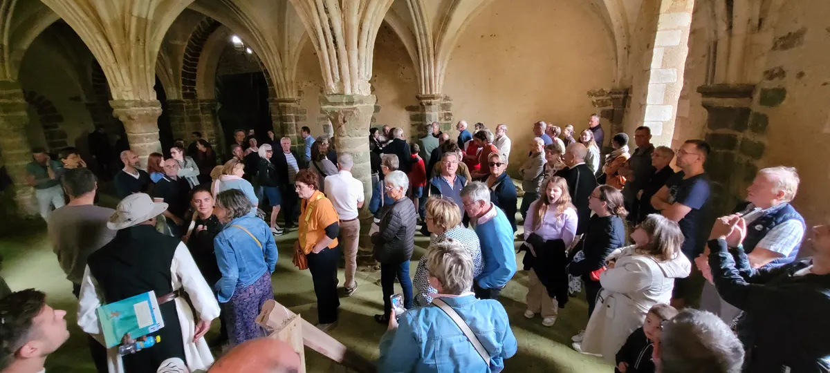 Un groupe de visiteurs rassemblés dans une salle voûtée aux colonnes de pierre
