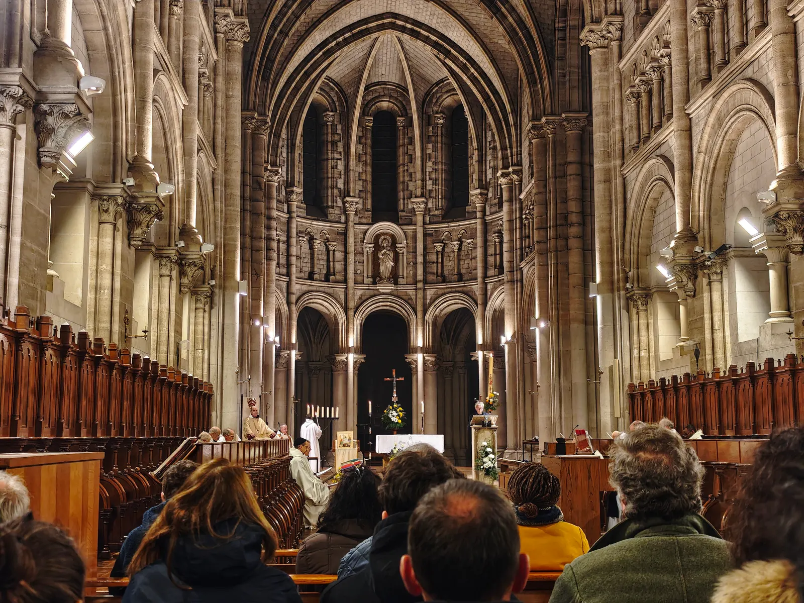 La nef de l’église abbatiale éclairée, l’assemblée debout et le célébrant à l’autel